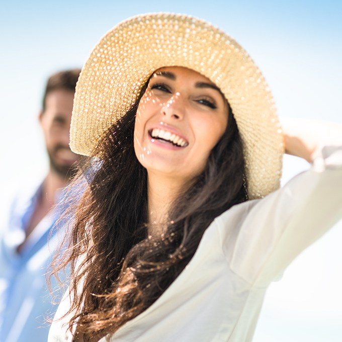 Smiling woman at beach after tooth colored filling restoration
