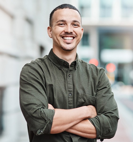 Man in button-up shirt smiling outside office building