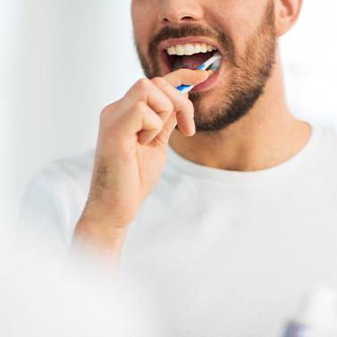 Man in white shirt brushing his teeth