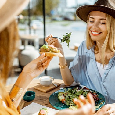 Two friends smiling while eating lunch outside