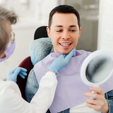 Man smiling at reflection in mirror with dentist