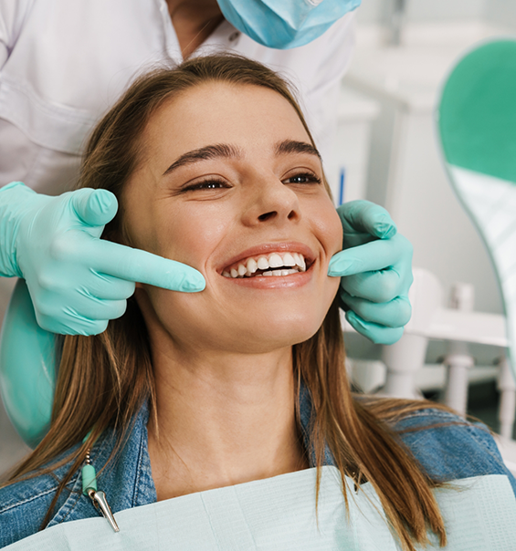 Young woman in dental chair beaming after cosmetic dentistry treatment