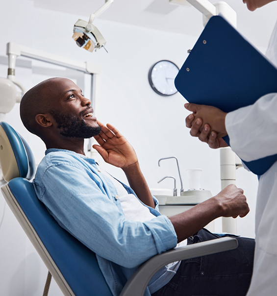 Dental patient talking to dentist while pointing to his mouth