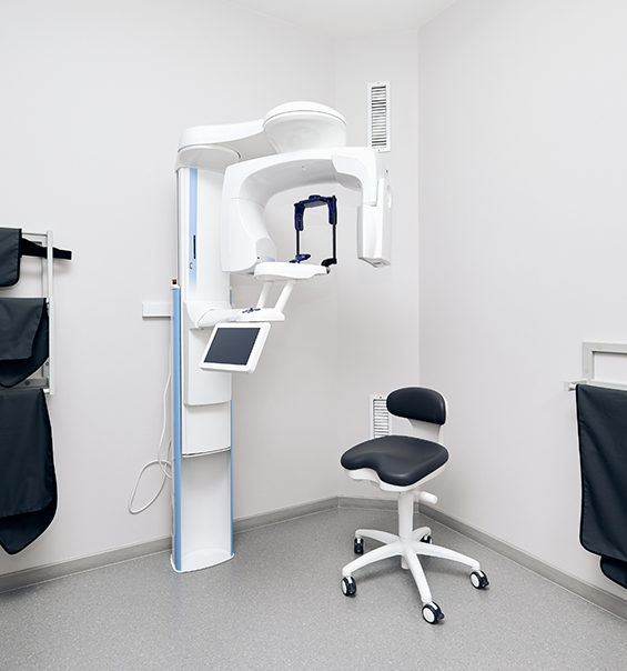 C T cone beam scanner standing against white wall of dental office