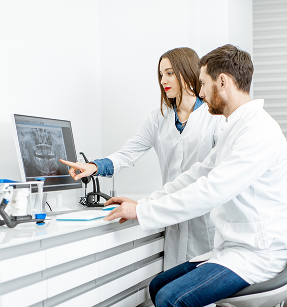 Two dental professionals looking at a computer showing an x ray of teeth