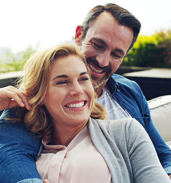 Smiling man and woman sitting on an outdoor couch