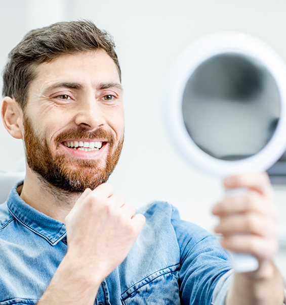 Dental patient looking at his new smile in a mirror