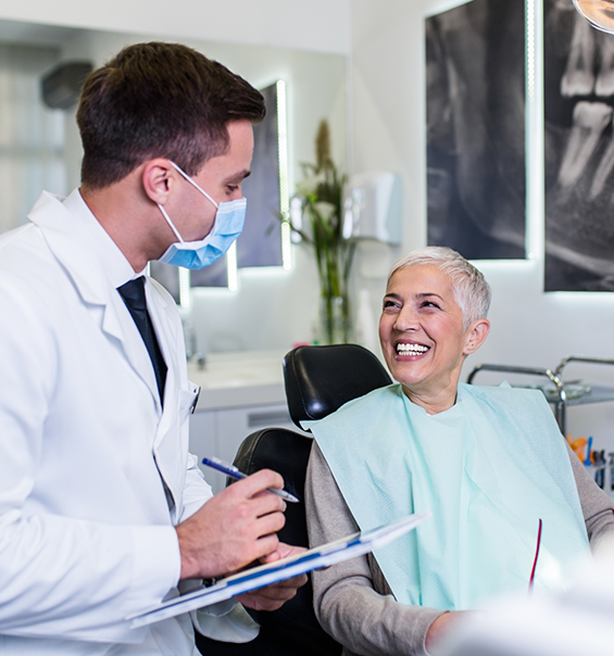 Senior woman in dental chair grinning at her dentist