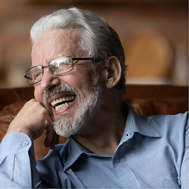 Senior man with glasses smiling and resting his chin in his hand