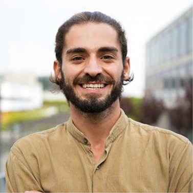 Young man with brown hair and beard grinning