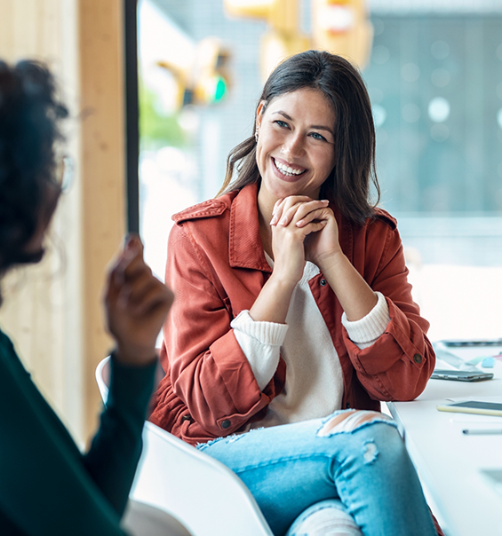 Woman in red jacket smiling at woman sitting across from her