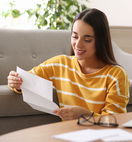 Young woman reading a paper while sitting on floor near couch