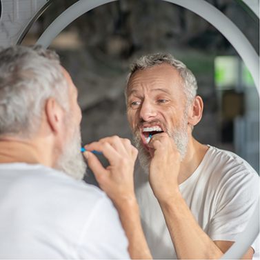 Senior man looking in mirror and flossing his teeth