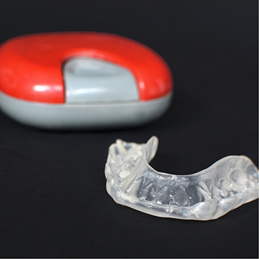 Clear mouthguard next to its storage case