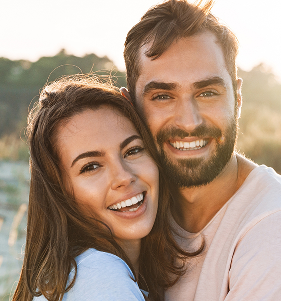 Young man and woman smiling together outdoors on sunny day