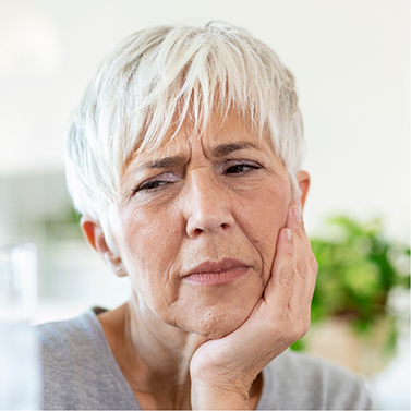 Senior woman touching her face and wincing in pain