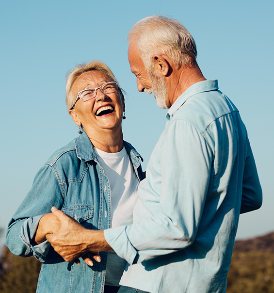 Senior couple in denim shirts laughing and holding hands outdoors