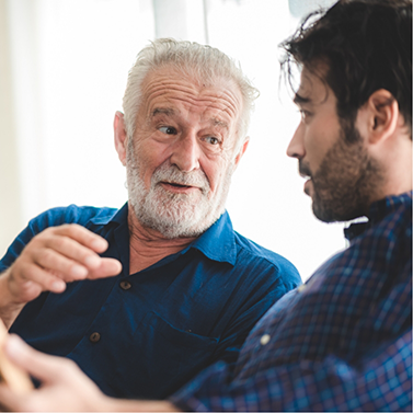 Senior man talking to younger man on couch