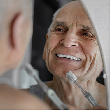 Senior man looking in mirror and holding toothbrush