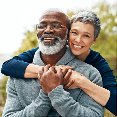 Smiling woman hugging a smiling man from behind