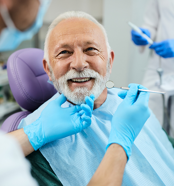 Senior dental patient smiling at his dentist