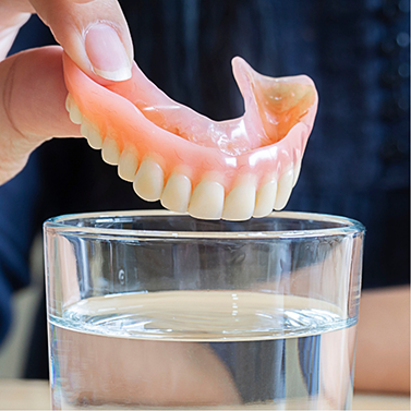 Person placing a denture in a glass of water