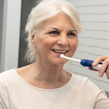 Smiling senior woman holding an electric toothbrush