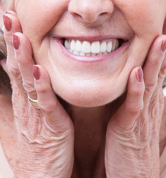 Close up of a smiling senior woman touching her face