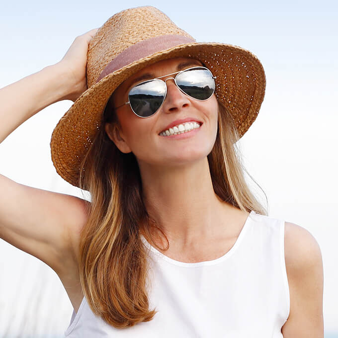 Smiling woman in sun hat after dental bonding treatment