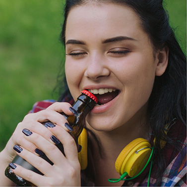 Woman opening up a side bottle with her teeth