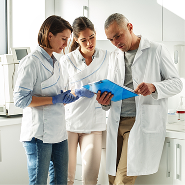 Three dental professionals looking at a clipboard together