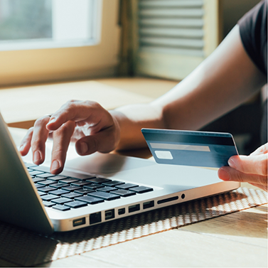 Person holding their credit card and typing on laptop