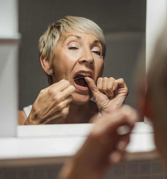 Senior woman flossing her teeth