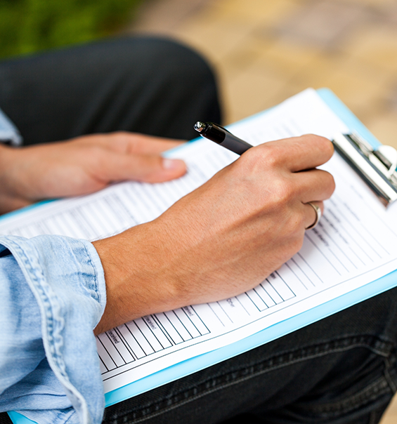 Person filling out paperwork on a clipboard