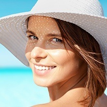 Smiling woman at beach with sun hat