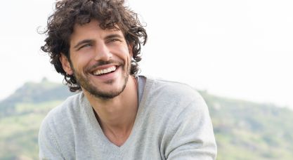 Man with curly brown hair sitting outdoors