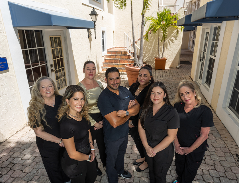 Palm Beach Dental Excellence team standing on cobblestone street in alley