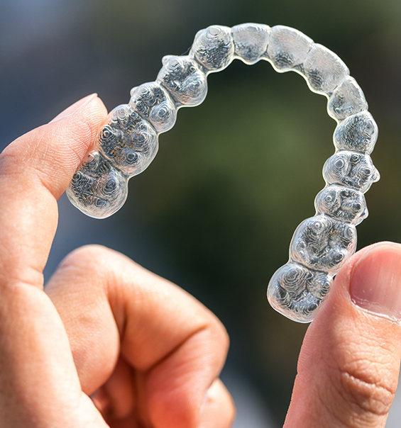 Hand holding a clear aligner in West Palm Beach