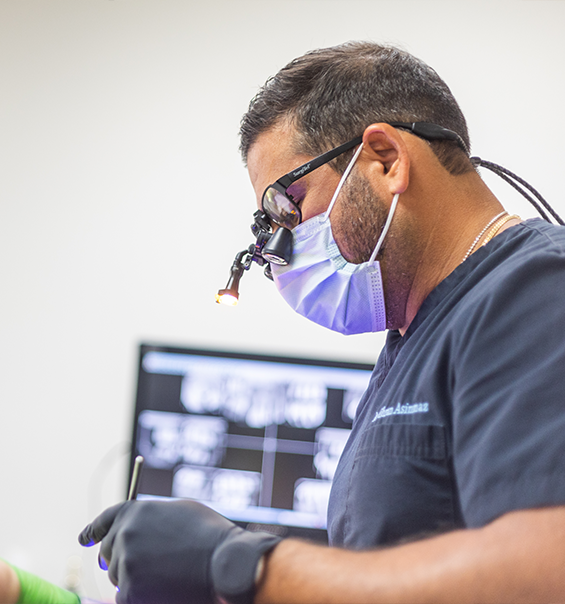 Doctor Asinmaz wearing dental binoculars while treating a patient