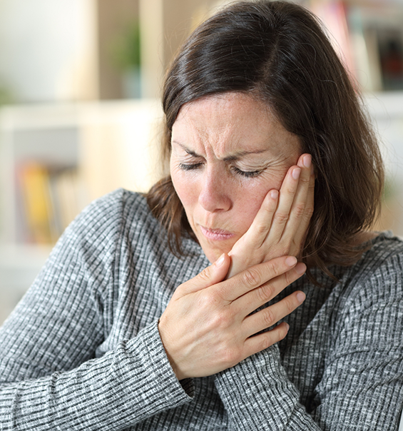 Woman holding her cheek in pain needing root canal treatment