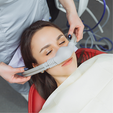 Woman in dental chair relaxing with nitrous oxide mask over her nose