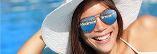 Young woman in sun hat at the pool after cosmetic dentistry