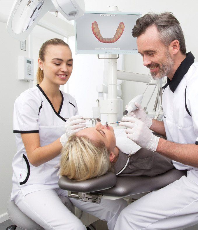 Dentist and dental team member examining a patient's mouth