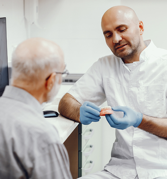 Dentist showing a senior patient a model of Teeth in a Day