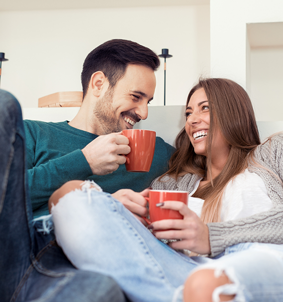 Man and woman drinking coffee on couch together