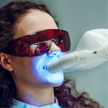 Woman having light shone on her teeth in dental chair