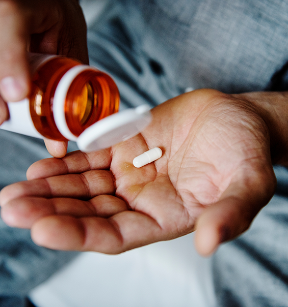 Person pouring a pill out of a bottle and into their hand