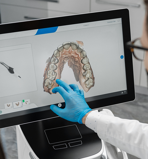 Dentist gesturing to a screen showing a digital impression of an arch of teeth