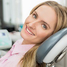 Woman smiling in dental chair during porcelain veneer treatment visit
