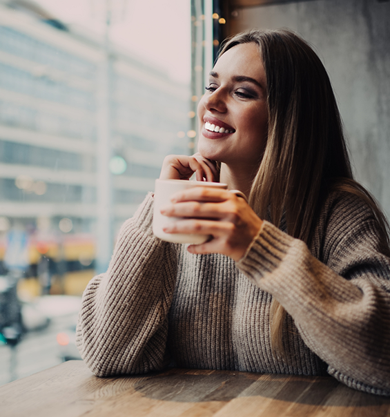 Woman holding a coffee mug at a table near a window